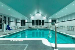 a swimming pool with tables and chairs in a building at Residence Inn by Marriott Orangeburg in Orangeburg