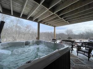 bañera de hidromasaje en un porche con nieve en el suelo en Gorgeous cabin 3bdrm/3bth, hot tub, fireplace, kid/pet friendly, en Galena