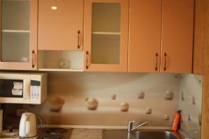 eine Küche mit weißen Schränken, einer Spüle und einer Theke in der Unterkunft Квартира на набережной in Pawlodar