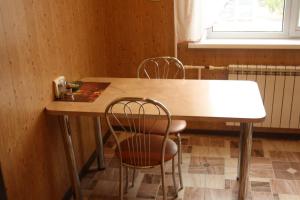 ein Tisch und Stühle in einem Zimmer mit Fenster in der Unterkunft Квартира на набережной in Pawlodar