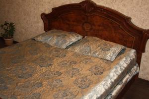 ein Bett mit einem Kopfteil aus Holz und zwei Kissen darauf in der Unterkunft Квартира на набережной in Pawlodar