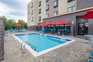 una piscina in un hotel con tavoli, sedie e ombrelloni rossi di TownePlace Suites by Marriott Dallas Mesquite a Mesquite
