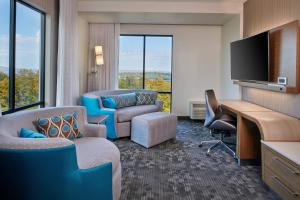 a hotel room with a desk and chairs and a tv at Courtyard by Marriott Petoskey at Victories Square in Petoskey