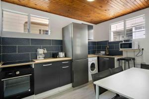 una cocina con electrodomésticos en blanco y negro y una mesa en Le Cataleya - Gîte "Terre et Truffes" en Le Lamentin