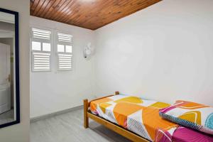 a bedroom with a bed in a white room at Le Cataleya - Gîte "Terre et Truffes" in Le Lamentin