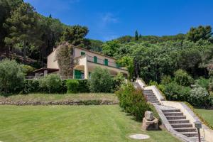 una casa su una collina con un cortile con scale di Villa Le Sprizze a bordo del mare - Goelba a Marciana Marina