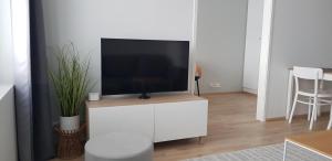 a living room with a television on a white cabinet at City Apartment with lake view and free parking in Kuopio