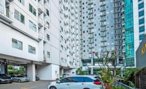 a car parked in a parking lot in front of tall buildings at Room Apartemen by GIANDARA in Sayang