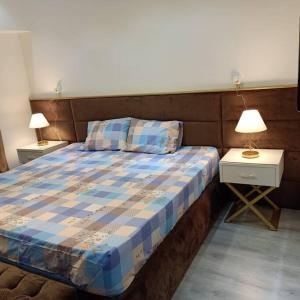 ein Schlafzimmer mit einem Bett und zwei Tischen mit Lampen in der Unterkunft 2 Bedroom+Garden, Lakes near AUC in New cairo