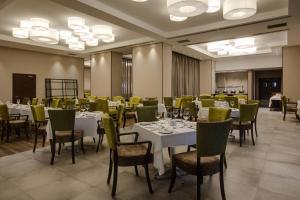 un comedor con mesas blancas y sillas verdes en Protea Hotel by Marriott Owerri Select en Owerri