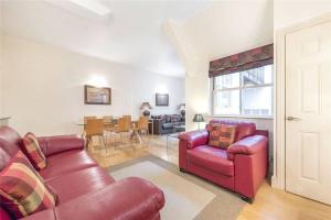 a living room with two red leather chairs and a dining room at Luxurious serviced apt next to the City of London and Tower Bridge in London