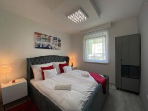 a bedroom with a bed with red pillows and a television at Sunshine Homes Zamárdi in Zamárdi