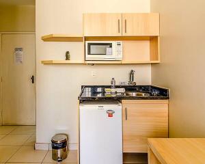 a kitchen with a white refrigerator and a microwave at Villa Neves Residence in Belo Horizonte