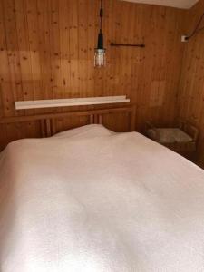 a bedroom with a white bed in a wooden wall at Romantisches Plätzchen in der Natur in Grindelwald