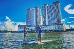 two men on paddle boards in the water with buildings at Best moments in Kuantan