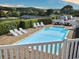 a swimming pool on a deck with chairs and a table at Springfields Bungalow in Exeter