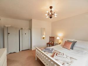 a bedroom with a white bed and a chandelier at Springfields Bungalow in Exeter