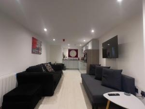 a living room with black couches and a kitchen at The Snap Pad Boutique Apartment in Royal Tunbridge Wells