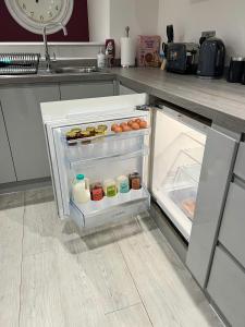 an open refrigerator in a kitchen with food in it at The Snap Pad Boutique Apartment in Royal Tunbridge Wells