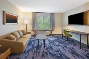 Fairfield Inn & Suites by Marriott Flint Grand Blanc في غراند بلانك: غرفة في الفندق مع أريكة وطاولة ومكتب