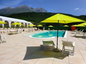 ein Pool mit gelben Sonnenschirmen und Stühlen neben in der Unterkunft Agriturismo Il Timo in Magliano deʼ Marsi