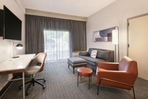 a living room with a couch and a desk in a hotel room at Courtyard by Marriott Burlington in Burlington