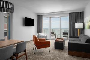 sala de estar con sofá, mesa y sillas en SpringHill Suites by Marriott Myrtle Beach Oceanfront en Myrtle Beach