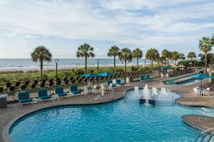 SpringHill Suites by Marriott Myrtle Beach Oceanfront في ميرتل بيتش: حمام سباحة على الشاطئ مع الكراسي والمحيط