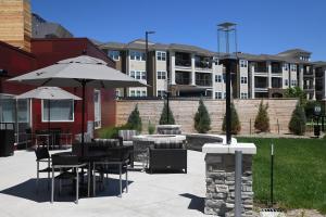 un patio con mesas, sillas y sombrillas en TownePlace Suites Kansas City At Briarcliff en Kansas City