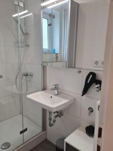 W łazience znajduje się umywalka oraz prysznic z lustrem. w obiekcie Liebevoll neu Eingerichtete Ferienwohnung in Zentraler Lage w mieście Monheim am Rhein