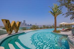 a swimming pool with a palm tree on a building at W Dubai - Mina Seyahi in Dubai