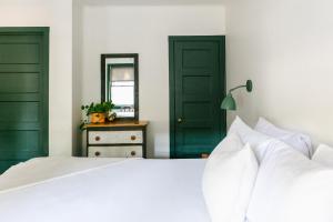 1 dormitorio con puertas verdes y 1 cama blanca en Piety Hill Cottages, en Nevada City