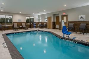 een zwembad in een hotellobby met stoelen en tafels bij Fairfield Inn & Suites Houston Katy in Katy