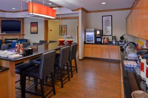 a restaurant with a bar with chairs and a kitchen at TownePlace Suites Detroit Warren in Warren