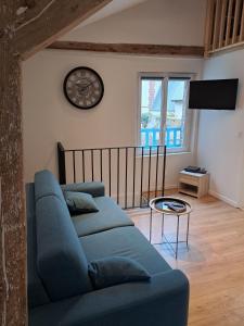 a living room with a blue couch and a clock at La plage logement de tourisme meublé - 3 étoiles in Villers-sur-Mer