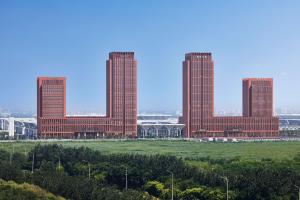 trzy wysokie budynki z czerwonej cegły z polem z przodu w obiekcie Tianjin Marriott Hotel National Convention and Exhibition Center w mieście Tiencin