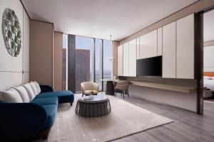 a living room with a blue couch and a tv at Tianjin Marriott Hotel National Convention and Exhibition Center in Tianjin