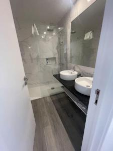 - une salle de bains blanche avec deux lavabos et une douche dans l'établissement top floor avenida arriaga 802, à Funchal