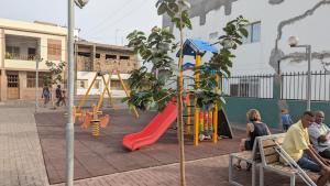 un parque infantil con un tobogán rojo y una estructura de juegos en My Flat en Praia
