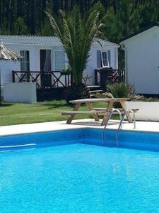 a picnic table sitting next to a swimming pool at Bungalow au bord de la piscine 4 pers 5A in Burinhosa
