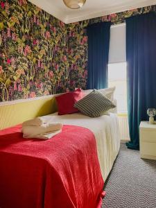 - une chambre dotée d'un lit avec une couverture rouge et du papier peint floral dans l'établissement Sheffield house on the hill, à Manor