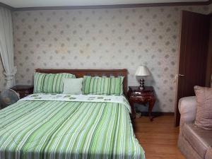- une chambre avec un lit doté de draps verts et d'un canapé dans l'établissement 3 Bedroom Condo Unit With View, à Baguio