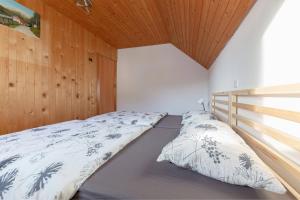 a bed in a bedroom with a wooden ceiling at Apartments Farm House Uric in Jesenice
