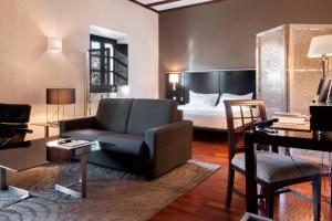 AC Hotel Palacio de Santa Ana by Marriott في بلد الوليد: غرفة معيشة مع سرير واريكة وكرسي