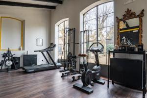 a gym with several tread machines and a mirror at Hotel Villa Maya in Cascina