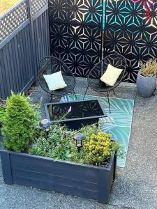 a black planter with plants and chairs and a fence at Mill Hill Haven in Victoria