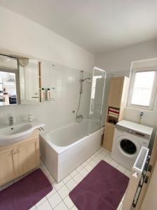 y baño con bañera, lavabo y lavadora. en cozy apartment close to vienna, en Brunn am Gebirge