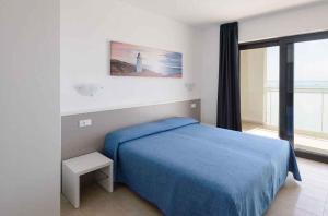 リニャーノ・サッビアドーロにあるApartments in Lignano 21632のベッドルーム(青いベッド1台、大きな窓付)