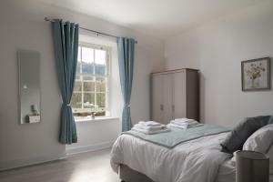 1 dormitorio con 1 cama con cortinas azules y ventana en Glan Conwy House One and Two Bedroom Apartments, en Llanrwst