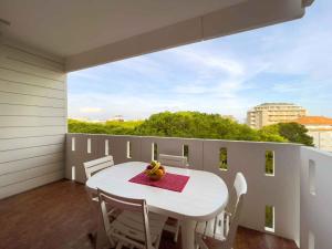un tavolo bianco e sedie su un balcone con finestra di Apartments in Lignano Sabbiadoro 21784 a Lignano Sabbiadoro